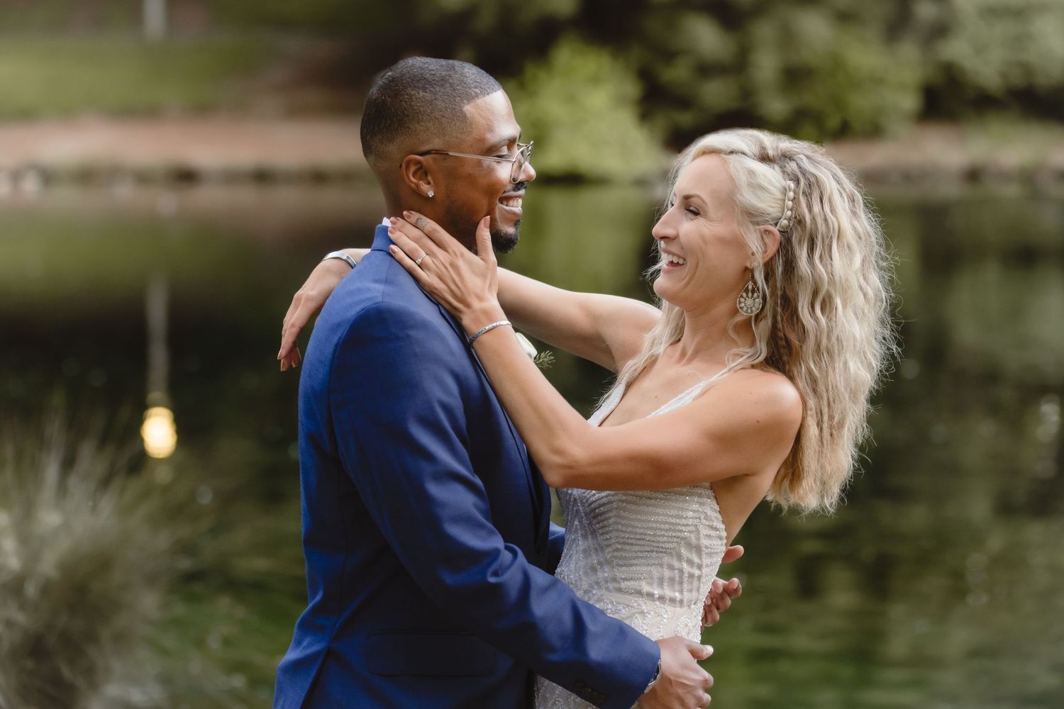 Happy couple shares an intimate moment by a serene pond during their wedding photoshoot.