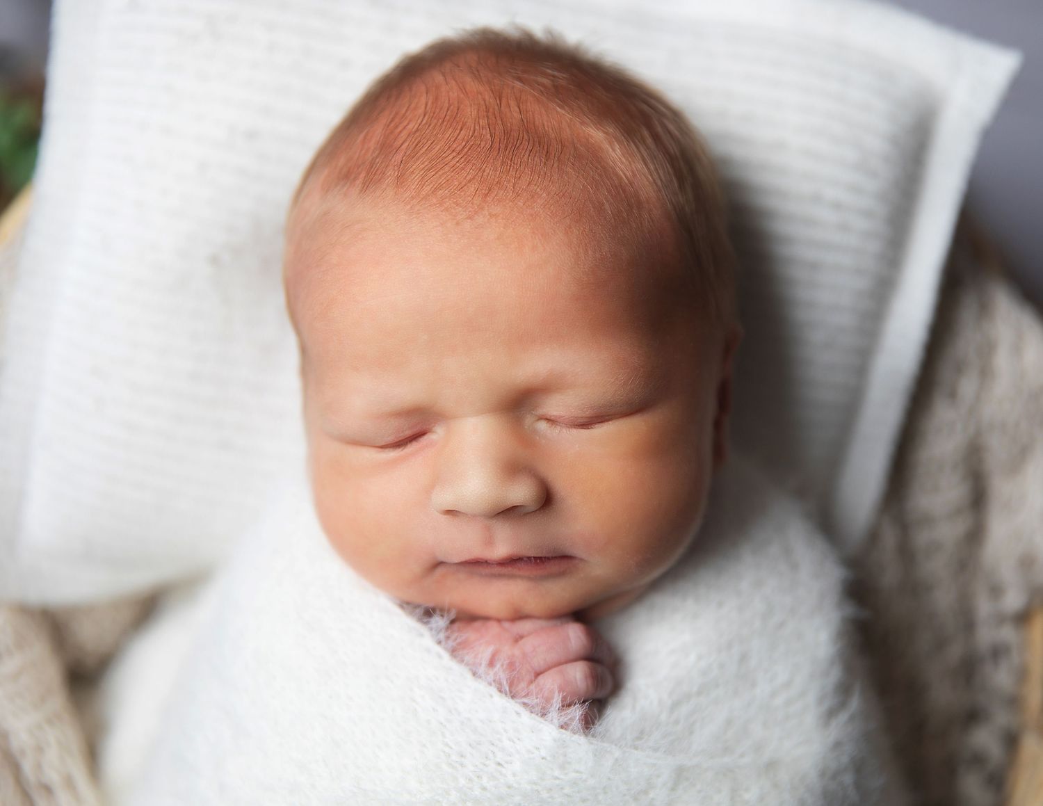 Peaceful newborn baby sleeping on a white pillow wrapped in soft blanket. During a photoshoot in Sidcup, Bexley