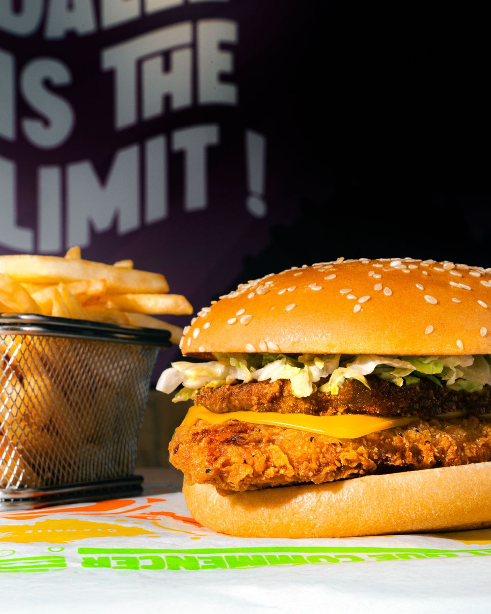 Crispy chicken sandwich with cheese and fries in metal basket against dark background. Mtlshutter photography