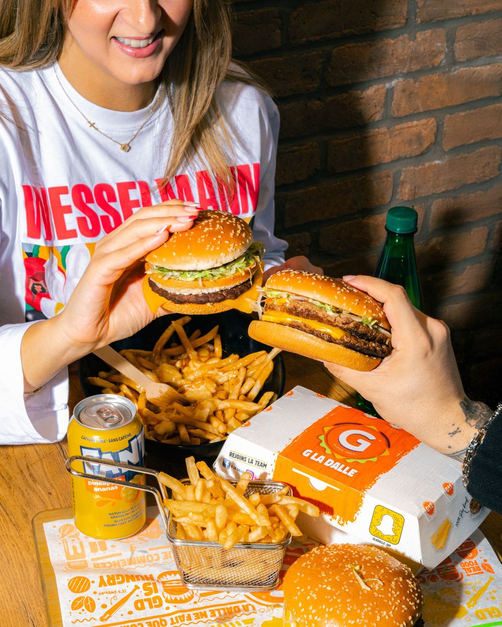 Multiple cheeseburgers and fries arranged on branded paper with drinks and takeout boxes.Mtlshutter photography