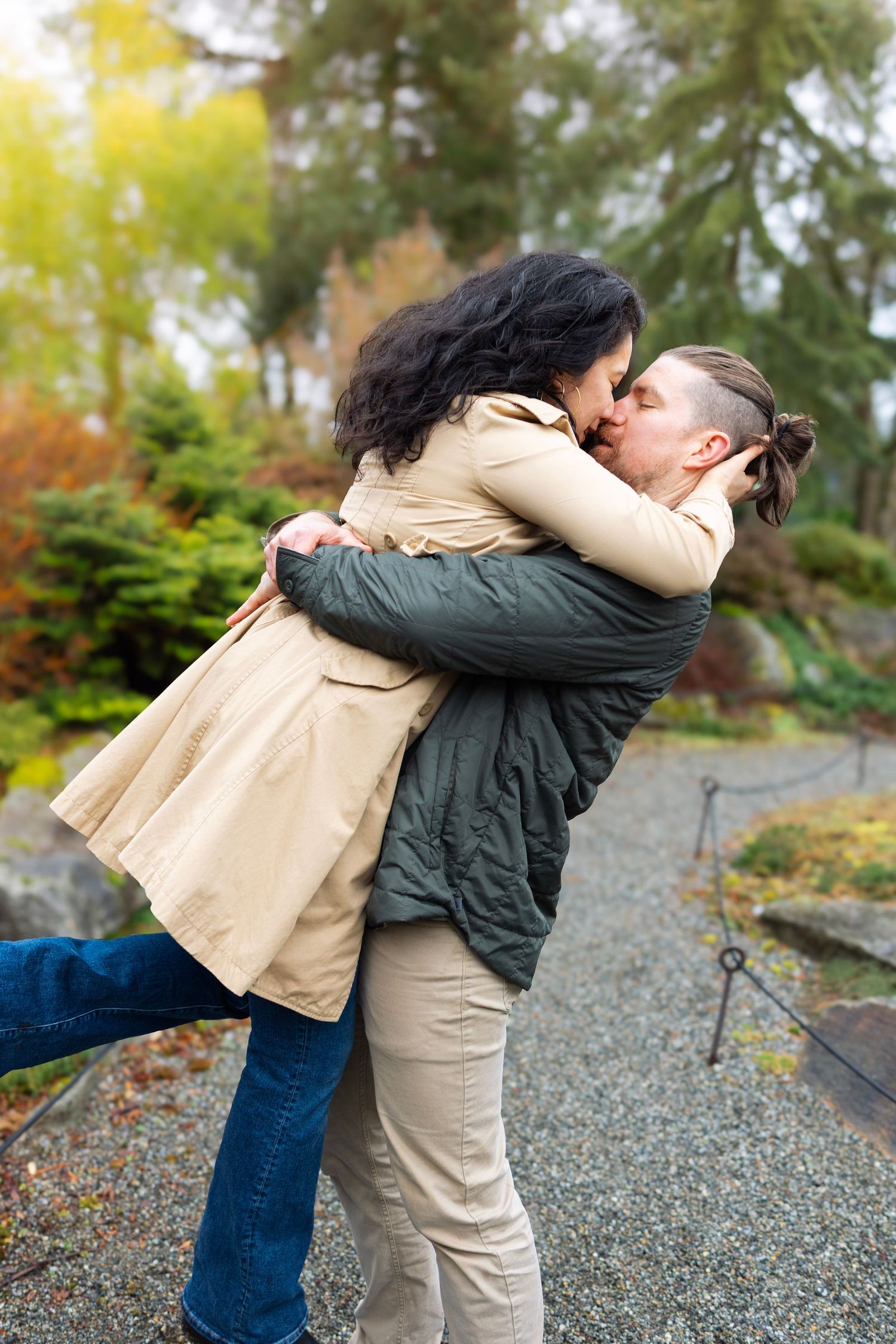 A couple embracing in a tender moment on a garden path surrounded by autumn foliage.