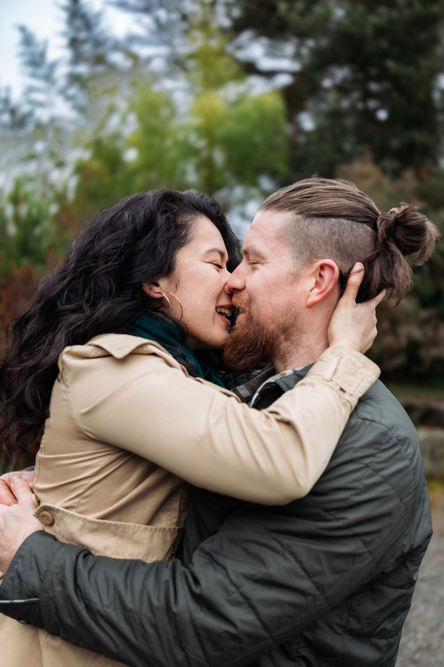 A joyful couple sharing a romantic kiss in a park setting during fall.