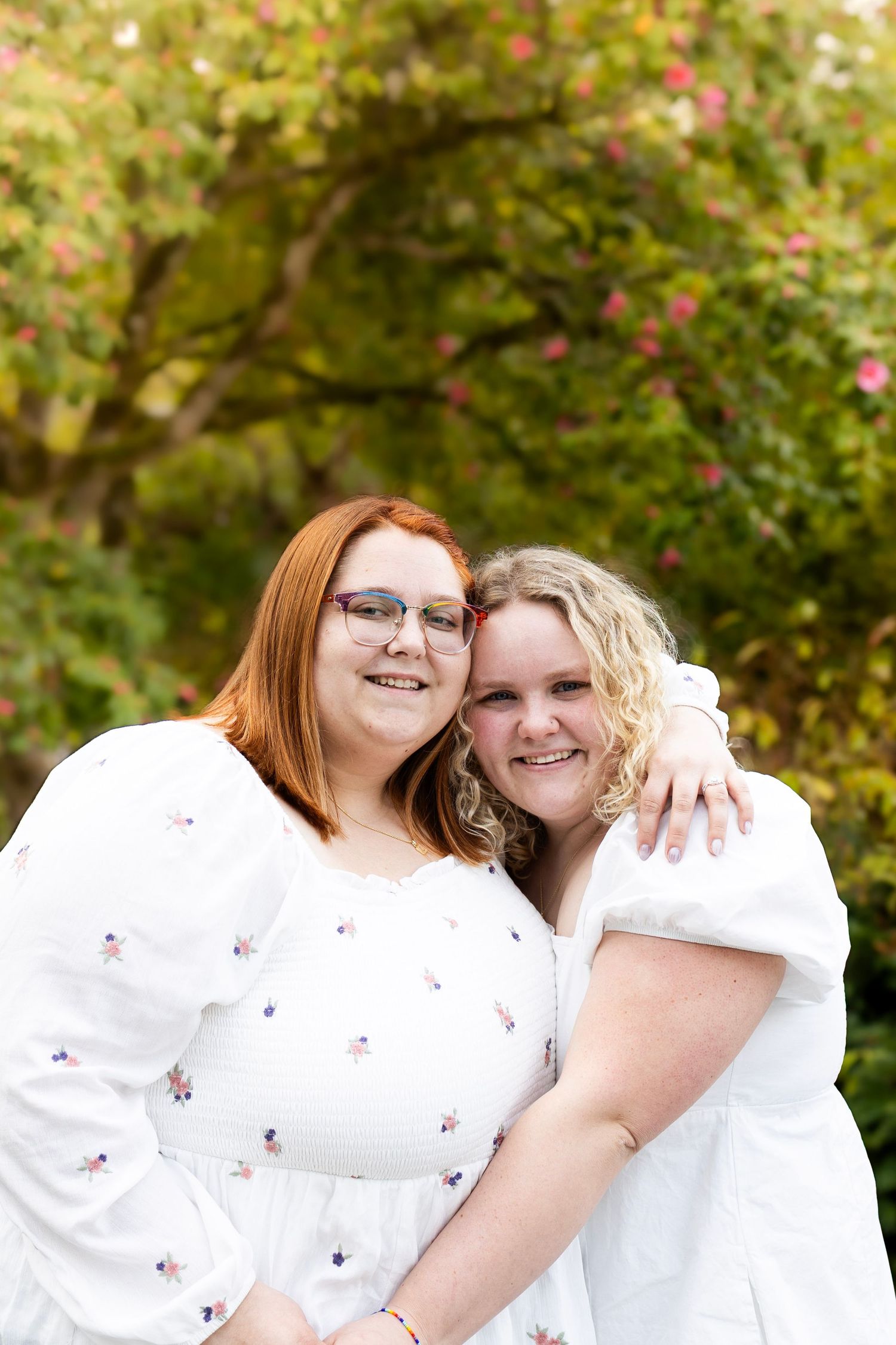 Two people in white tops share joyful moments together against a natural outdoor backdrop.