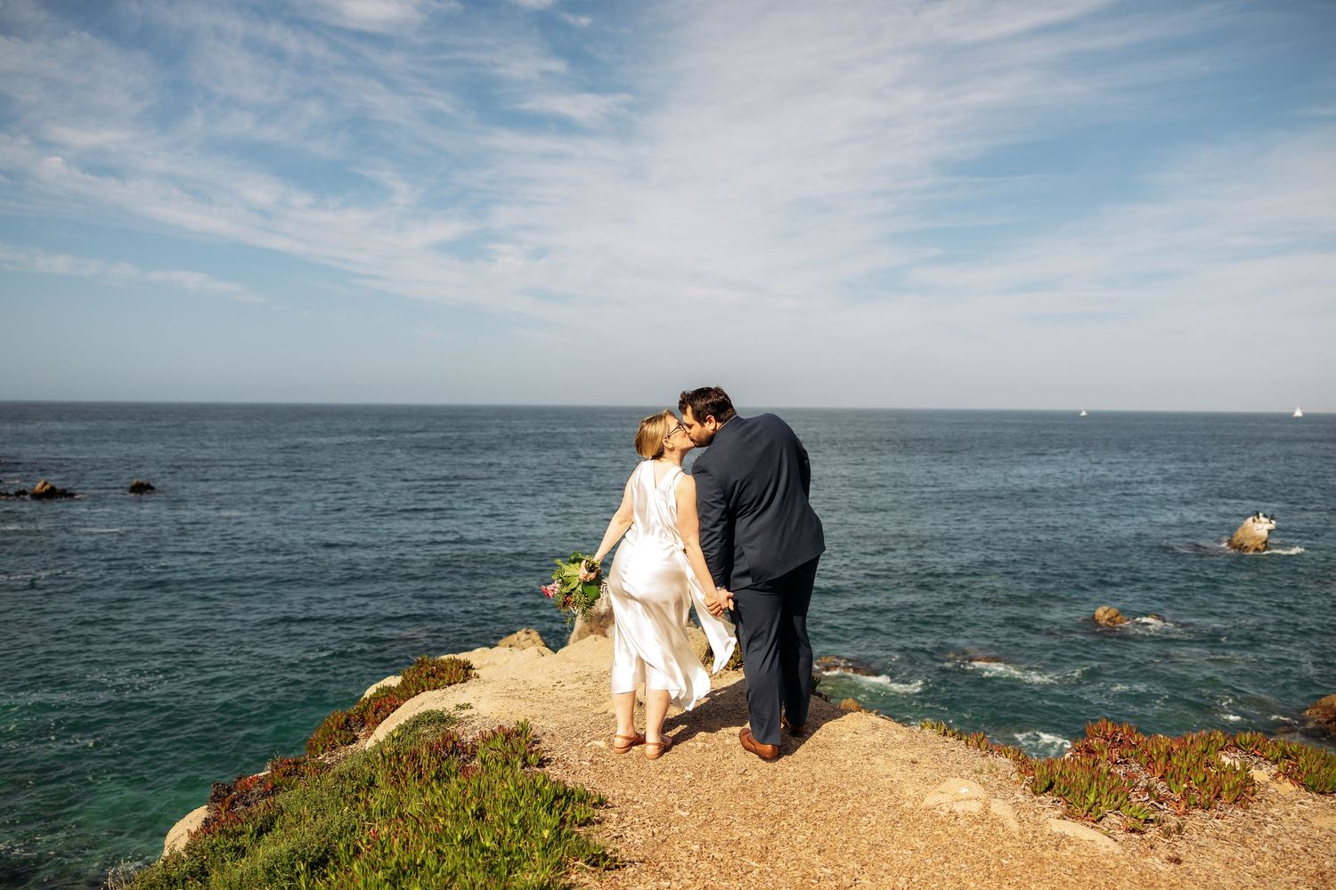 Scenic coastal engagement photoshoot on dramatic cliffs overlooking the Pacific Ocean on a bright sunny day.