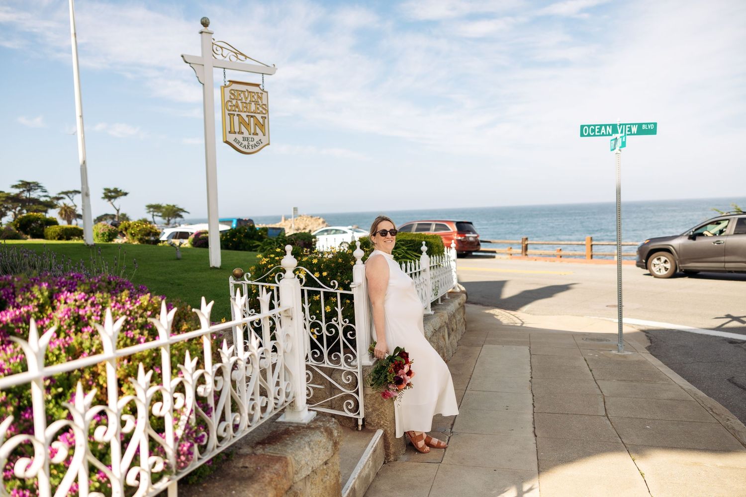 A panoramic view of a beachfront boardwalk with white railings and ocean waves visible in the distance.