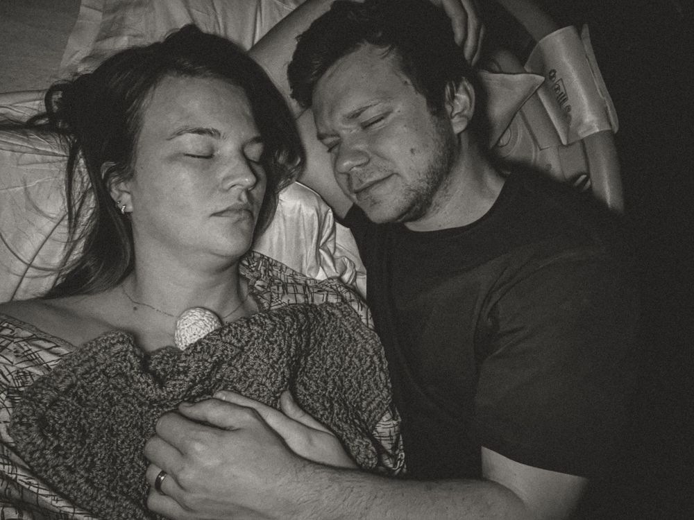 A black and white photograph shows two people sleeping peacefully together on a bed.