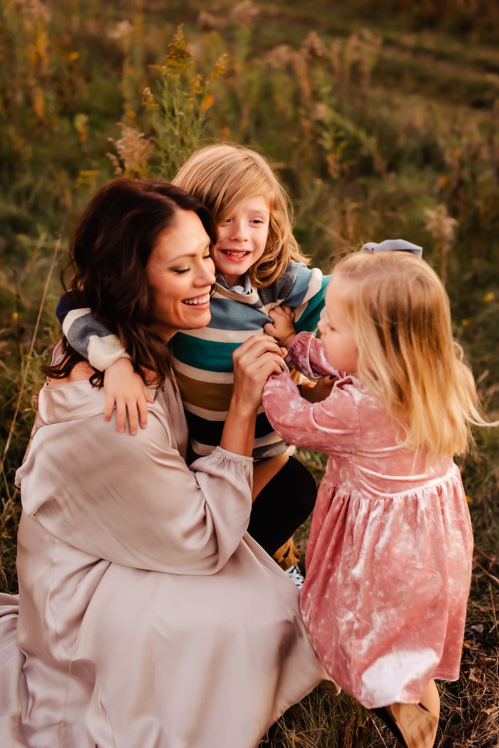 Happy family playing and laughing together in an autumn field during golden hour.
