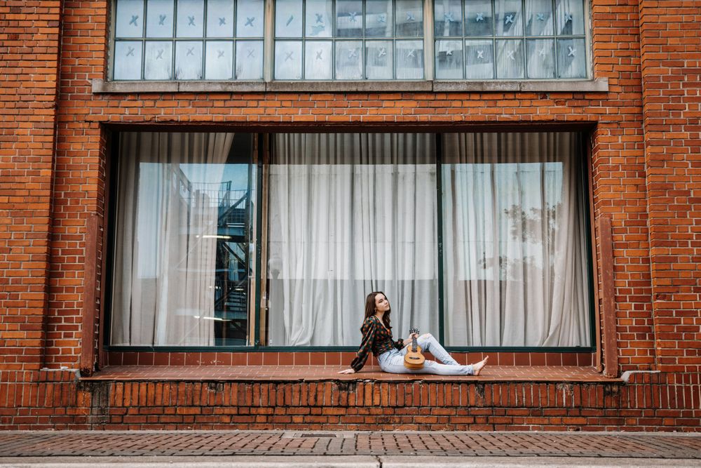 Red brick building exterior with large windows and white curtains.