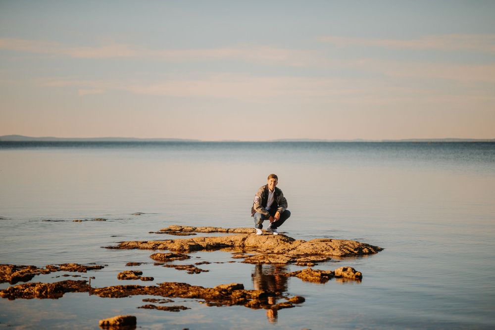 Serene coastal landscape with rocky outcrops and calm waters during sunset.