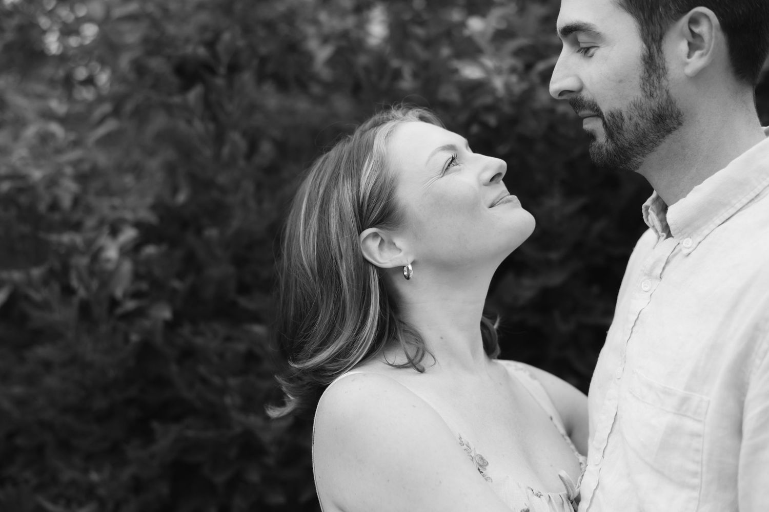 A romantic black and white portrait of a couple sharing an intimate moment outdoors.