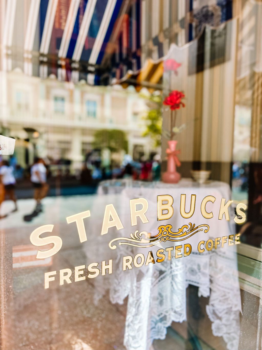 Elegant Starbucks window signage with gold and white lettering displays 'Fresh Roasted Coffee' in a vintage style.