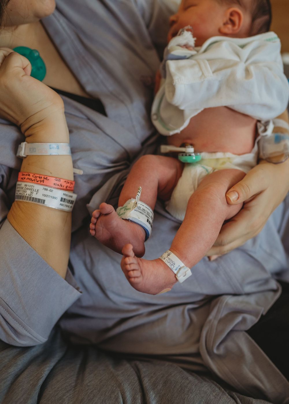 Hospital identification bands and monitors on newborn's feet and arms.