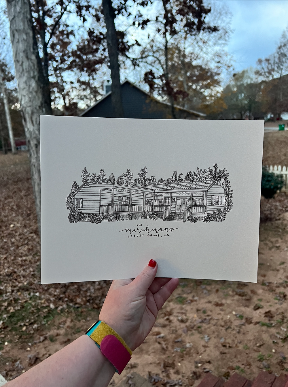 Pen sketch of a long modern house design with decorative foliage held against a fall landscape.
