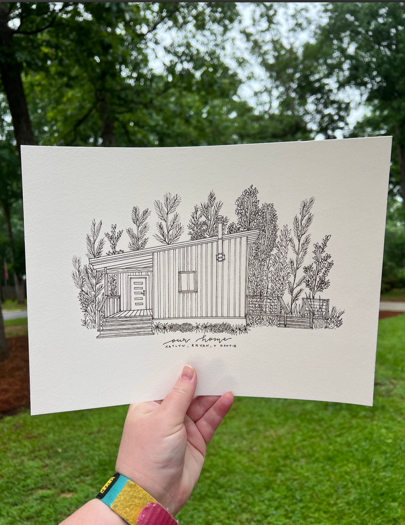 Black and white illustration of a modern tiny house with surrounding plants and trees.