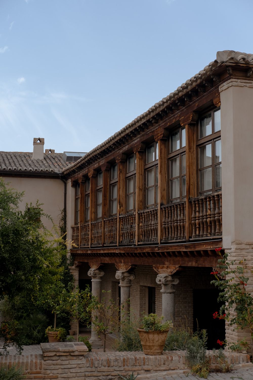 Historic Spanish colonial building with wooden balcony and stone pillars in Mediterranean style.