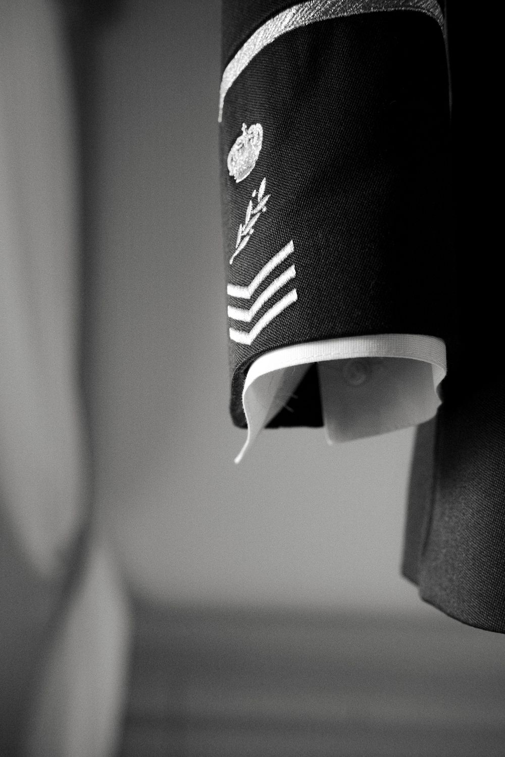 Close-up black and white detail of military uniform sleeve showing rank stripes.