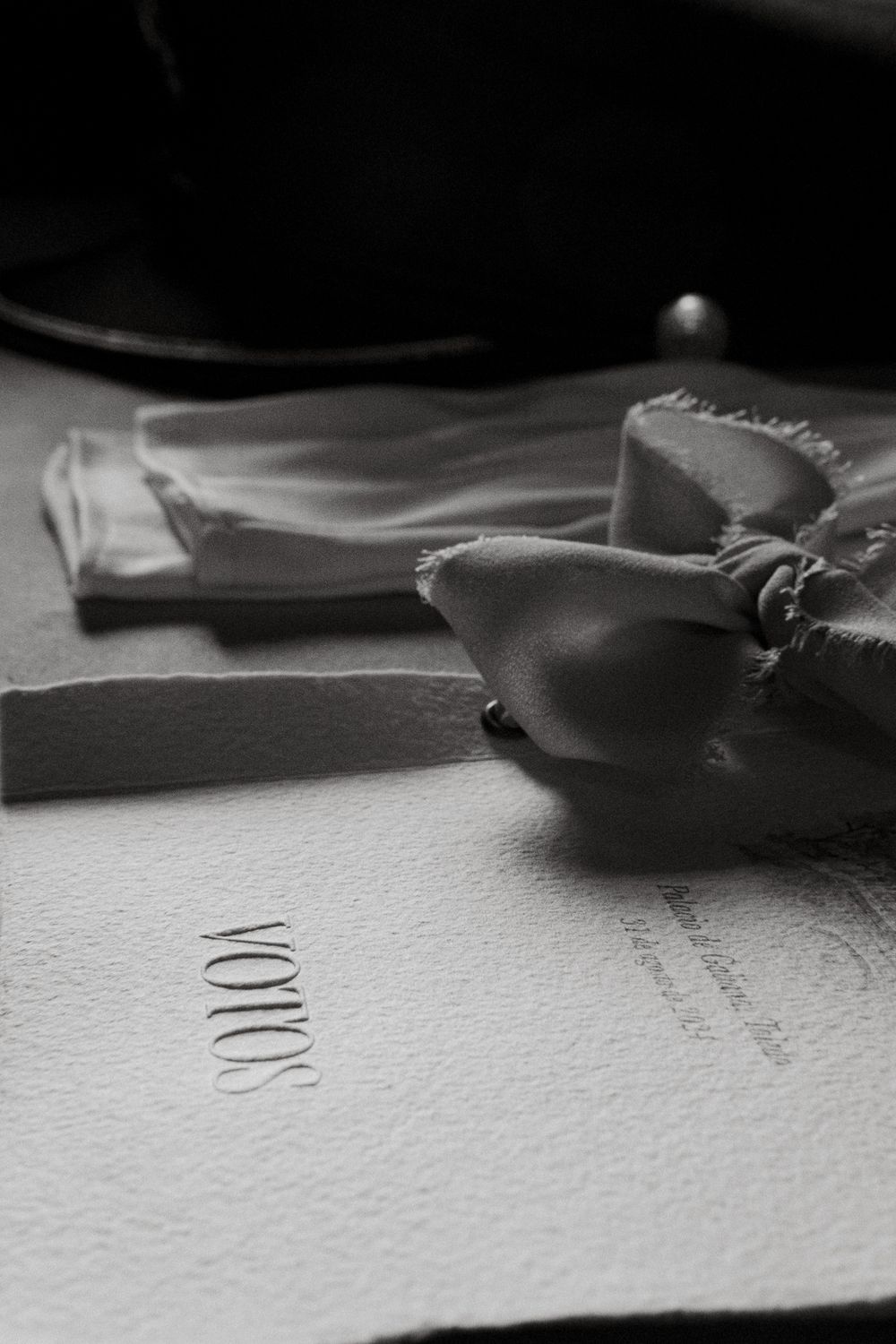 Wedding vow booklet with decorative bow photographed in dramatic black and white.
