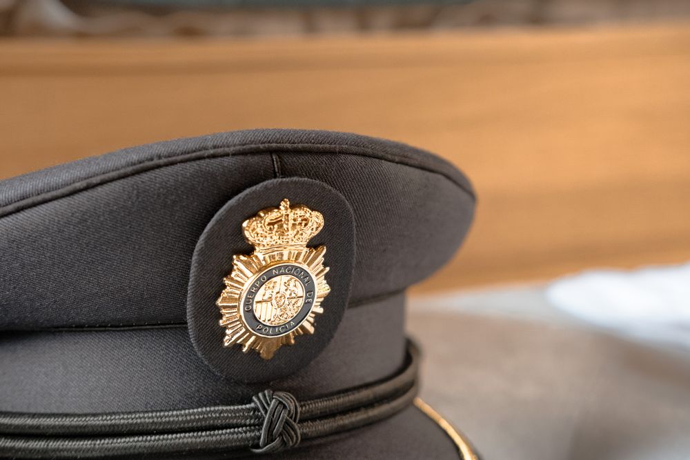 Police or military cap with golden crown emblem displayed against wooden background.