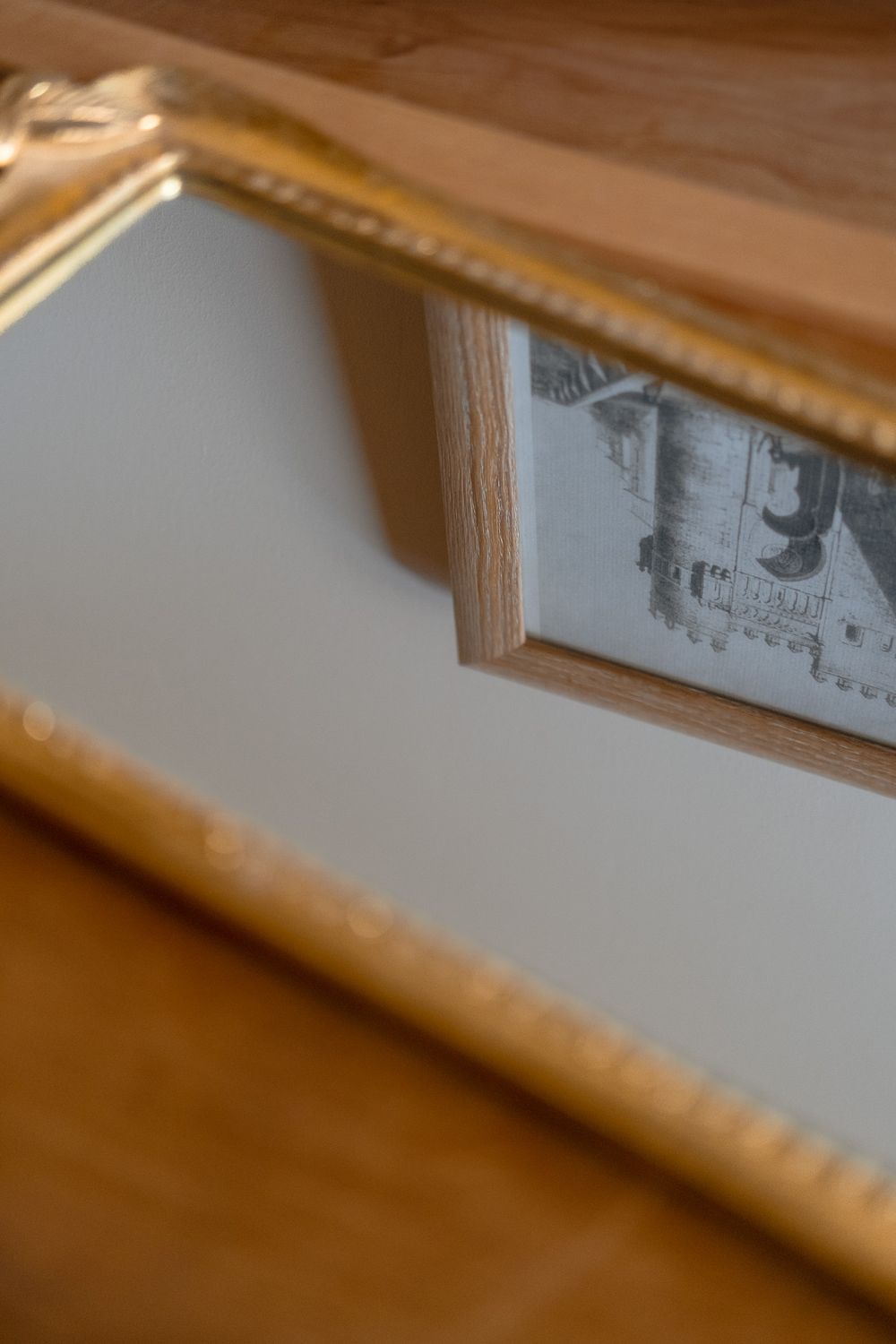 Close-up view of a wooden picture frame corner showing partial reflection in mirror.