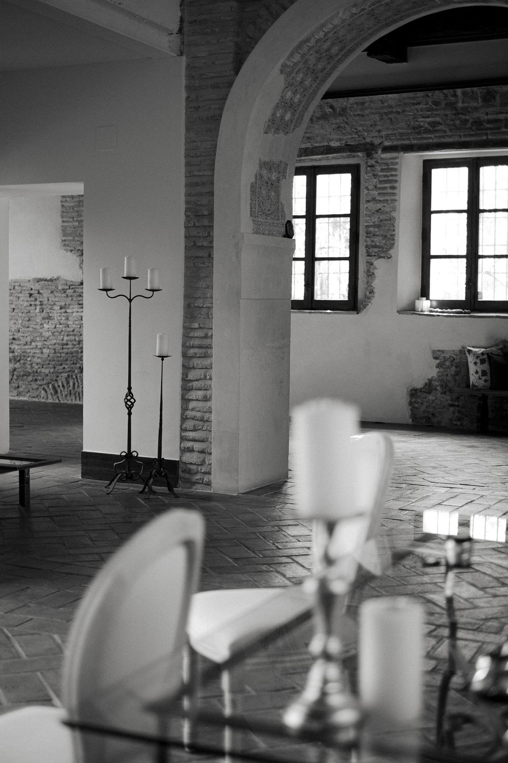 Interior room with brick archway, windows, and candlestick holder in black and white.