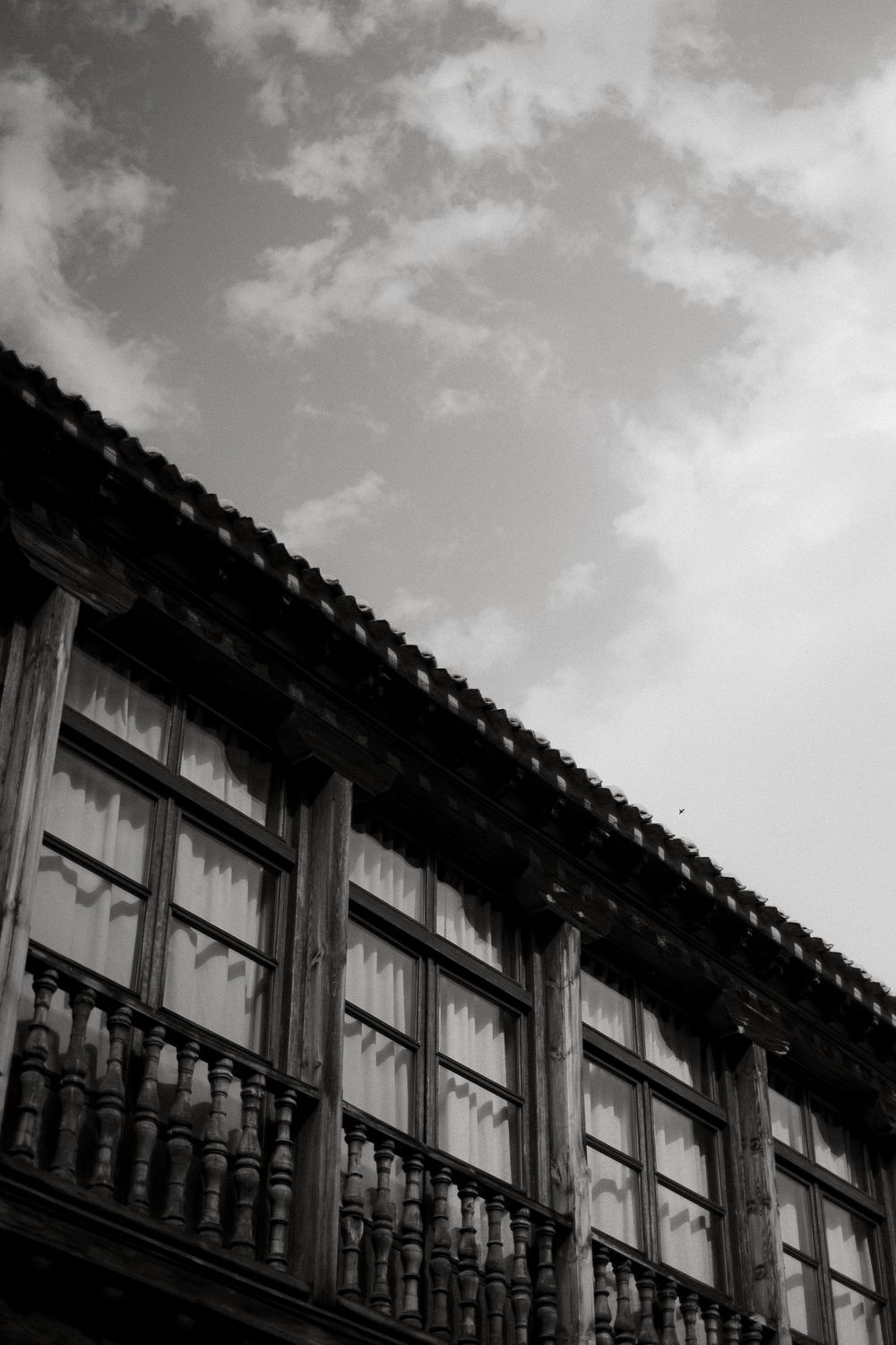 Black and white architectural detail of traditional windows with wooden balcony railings.