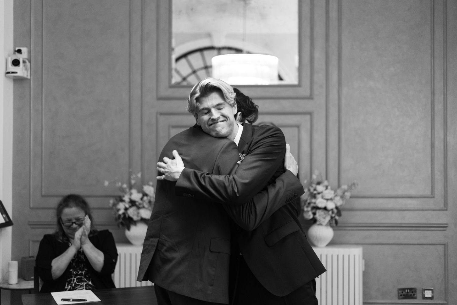Two people share an emotional embrace during a touching black and white wedding moment.