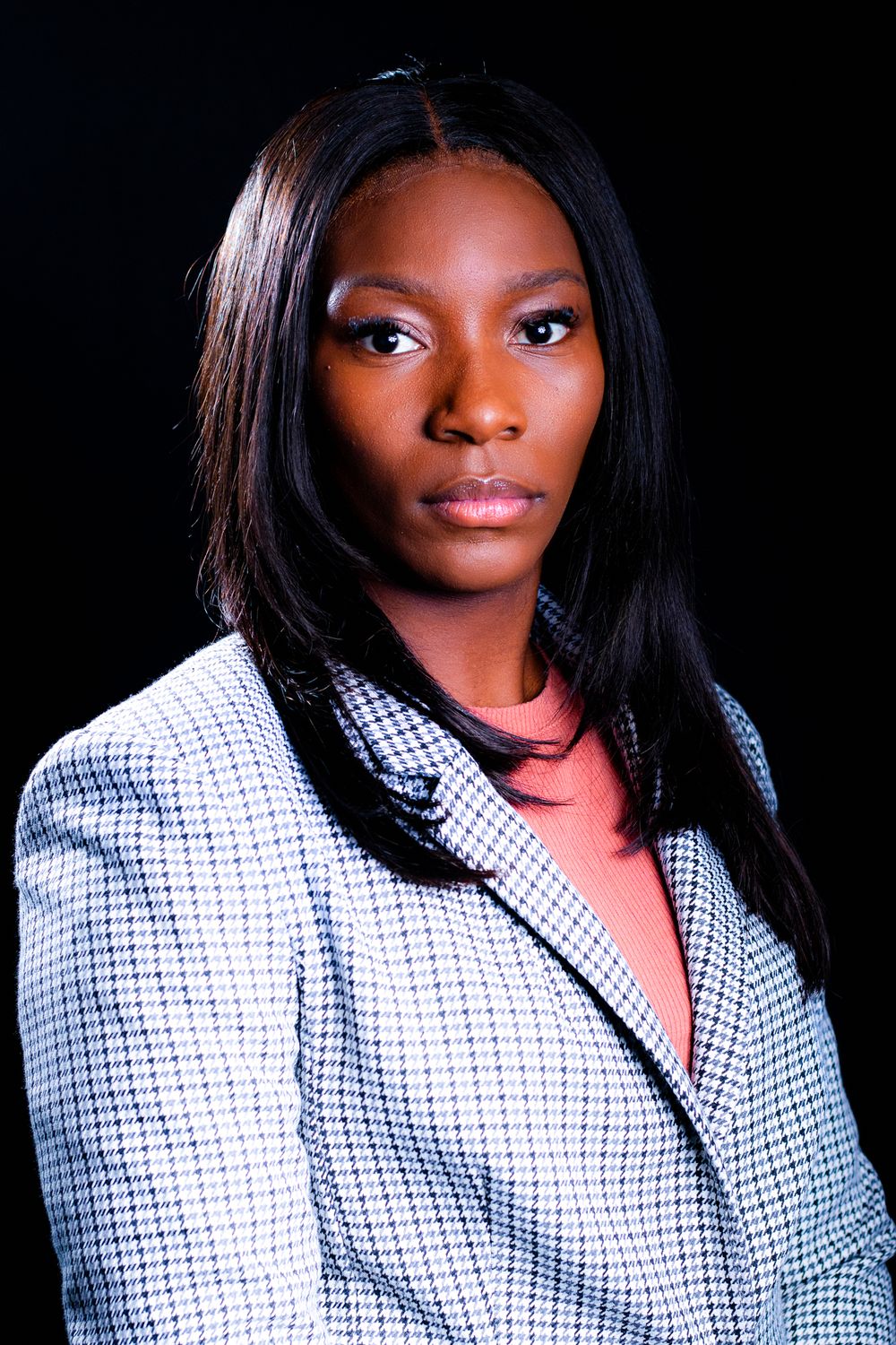Professional portrait series showing elegant styling with a black and white checkered blazer against dark background.