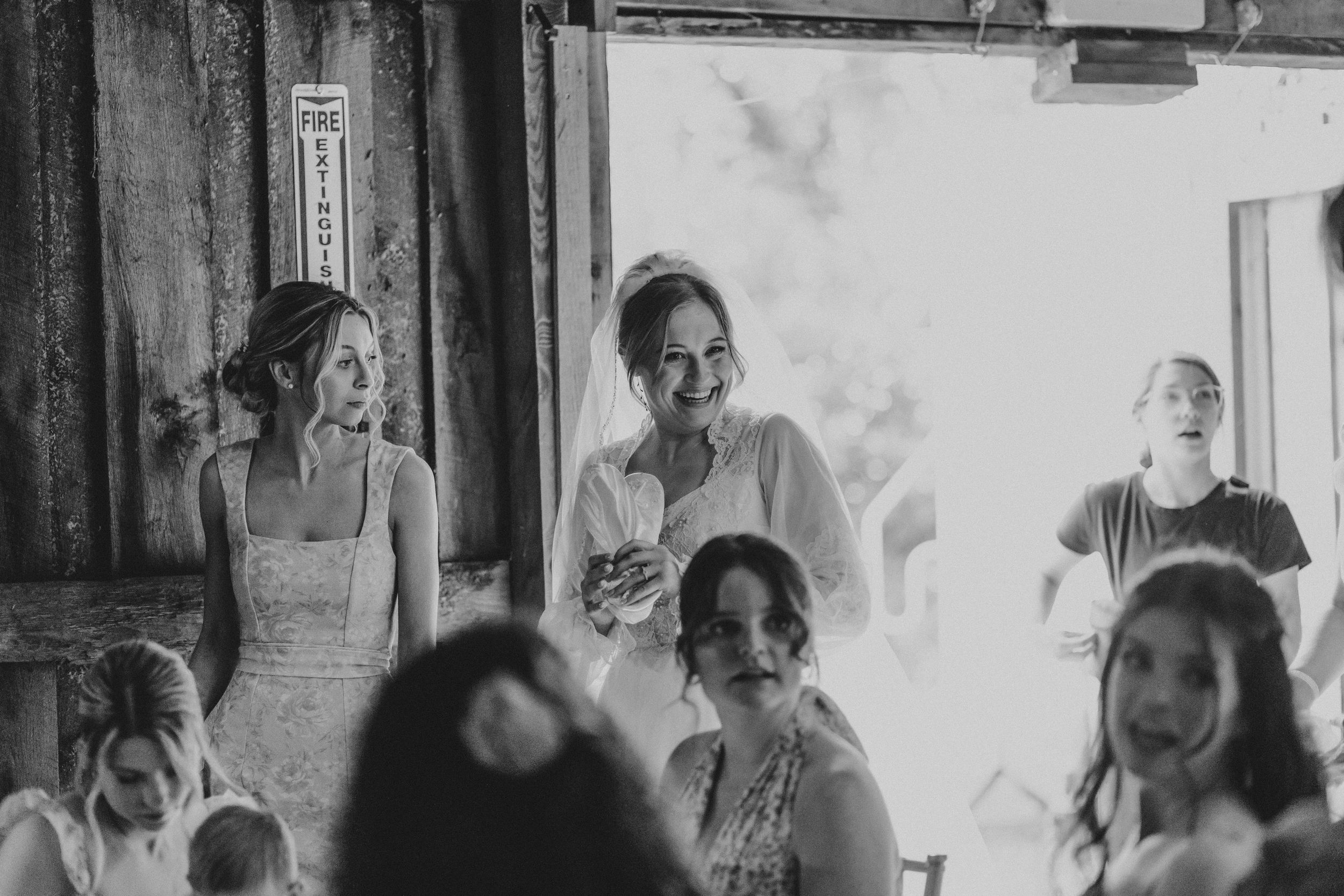 A black and white photograph showing a group of women in formal attire gathered together, smiling and laughing.