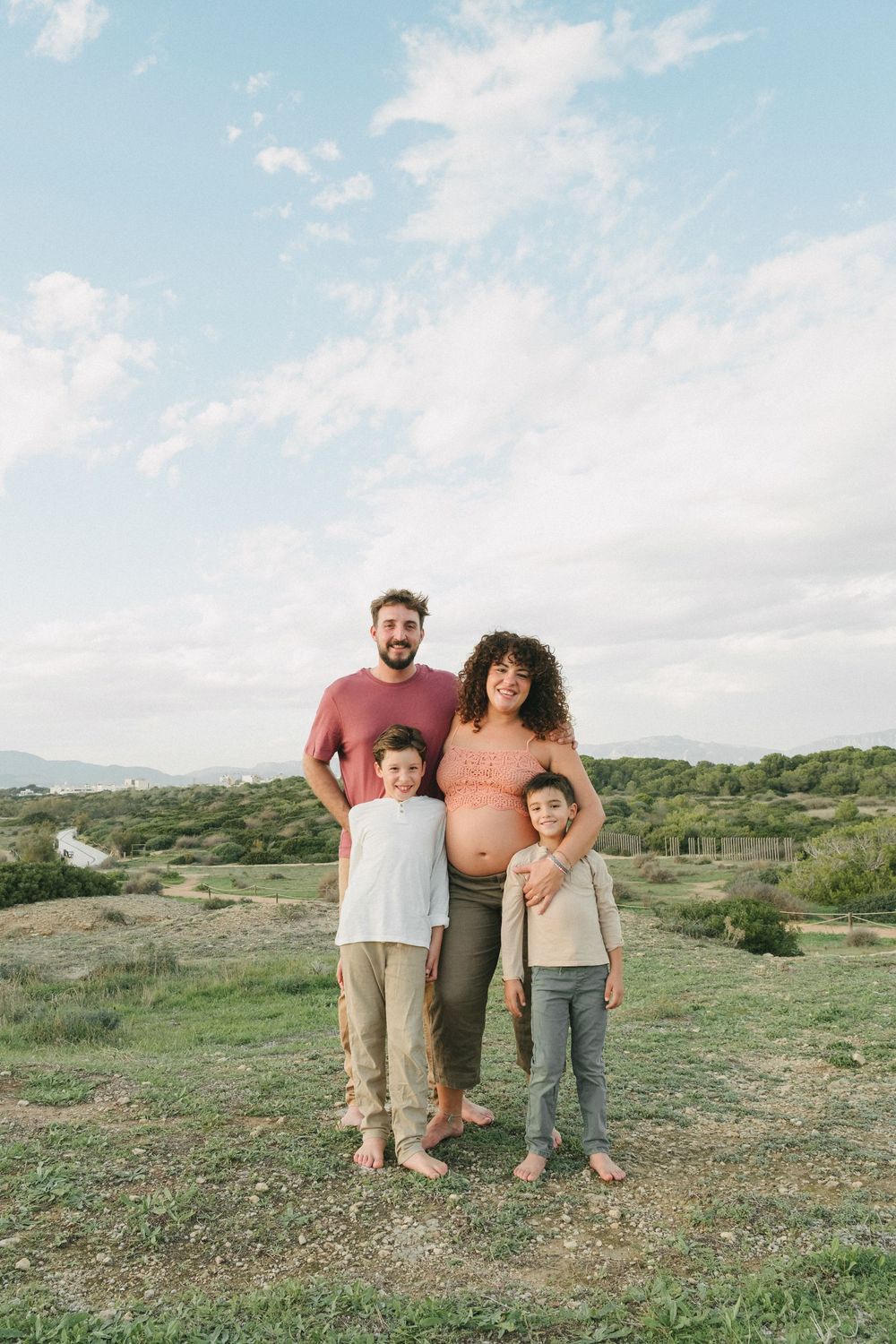 A family enjoys a casual outdoor photo session in a scenic desert landscape during golden hour.