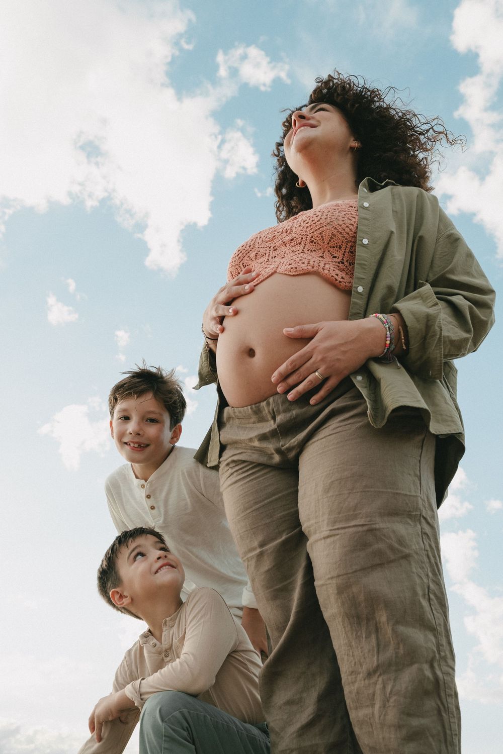 foto de maternidad con niños con cielo azul y nubes blancas de fondo