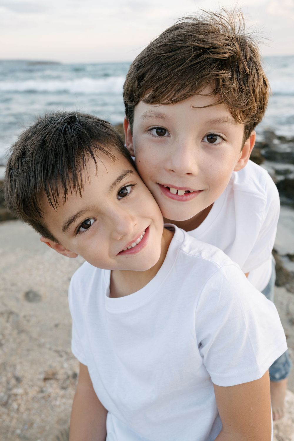 niños de cinco y siete años con camiseta blanca en la playa