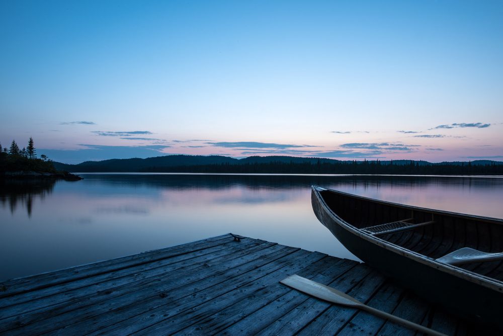 Tranquil lake scene with wooden docks extending into still waters at dusk.