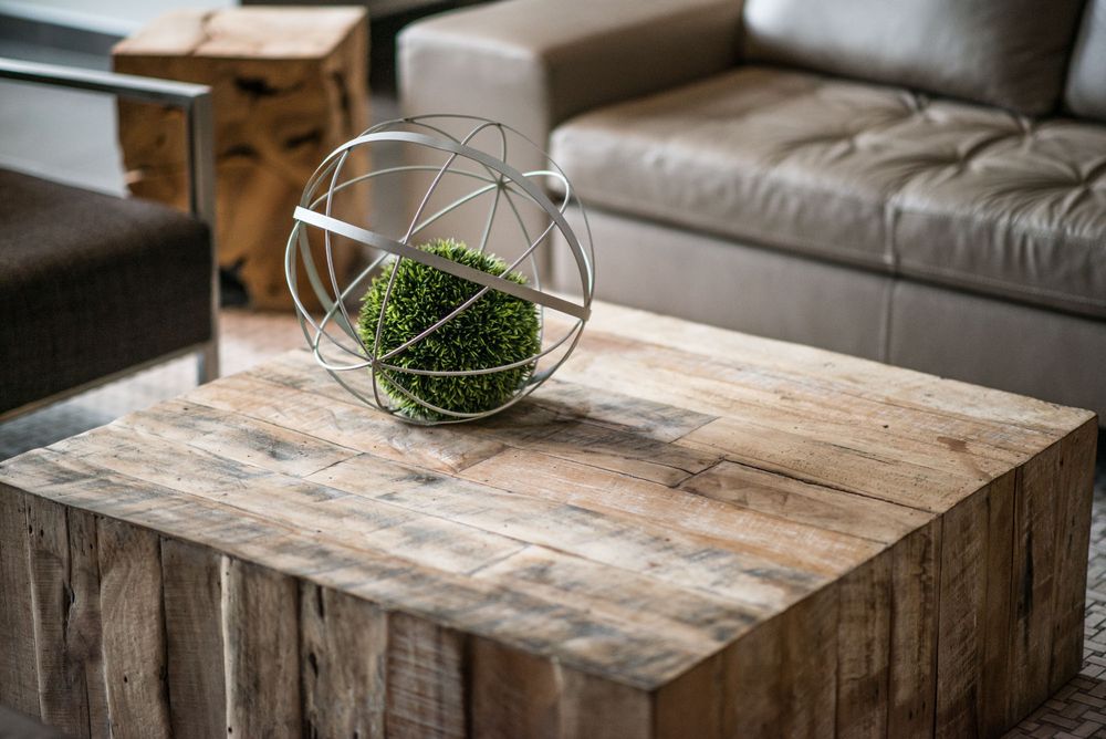 Rustic wooden coffee table with distressed finish and decorative glass vase in modern living room.