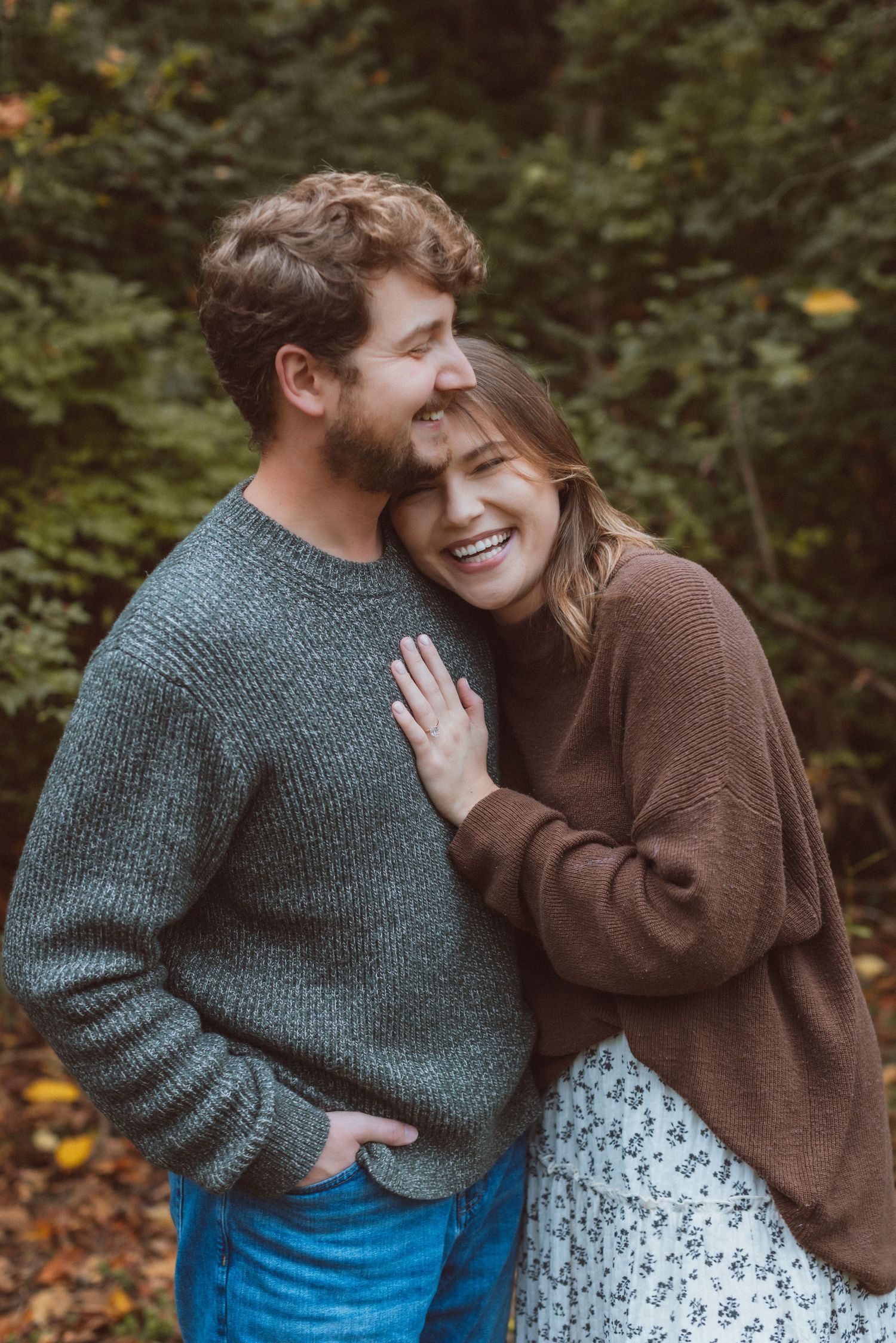 A woman leans against a man's shoulder and laughs during an engagement photography session in Kansas City, Missouri.
