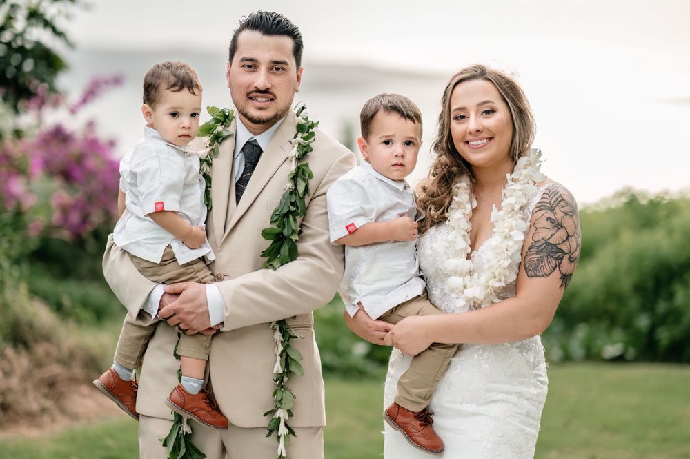 Wedding couple and child share tender moments in a lush garden setting with tropical flowers.