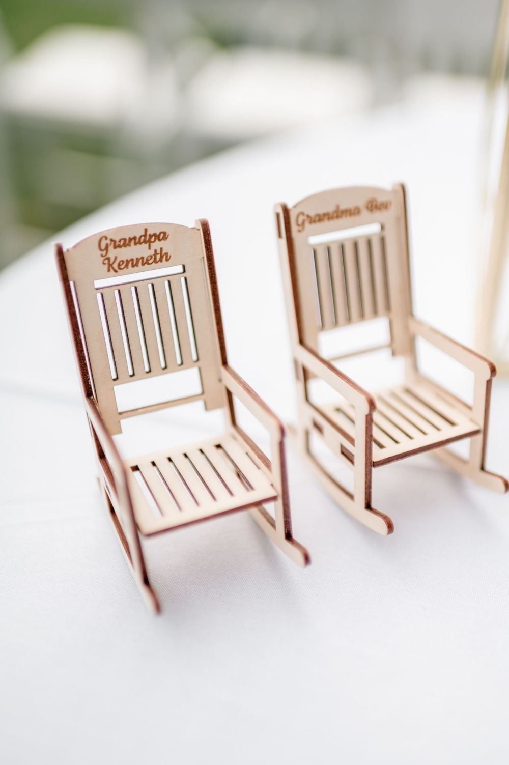 Miniature wooden bench place card holders lined up on white surface.