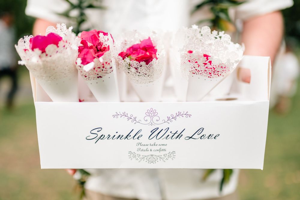Pink confetti-filled wedding favors arranged in white display boxes.
