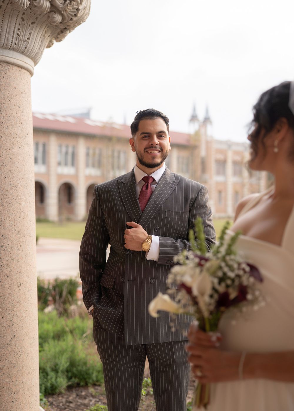 Rubi and Joe walking hand in hand on the paths of Rice University for their wedding portrait session, with sunlight filtering through trees