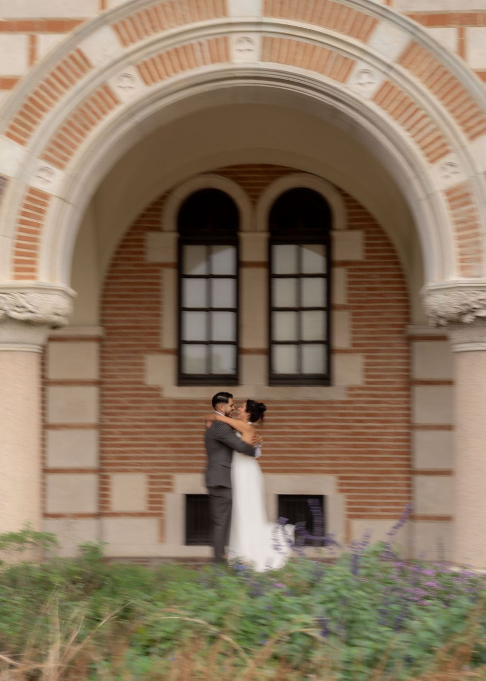 Wedding portraits of Rubi and Joe Yerena in front of Rice University’s iconic Lovett Hall, showing their love and connection.
