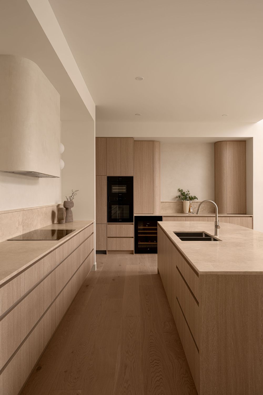 Sleek modern kitchen interior with white cabinets, dark wood flooring, and built-in appliances in a minimalist design.