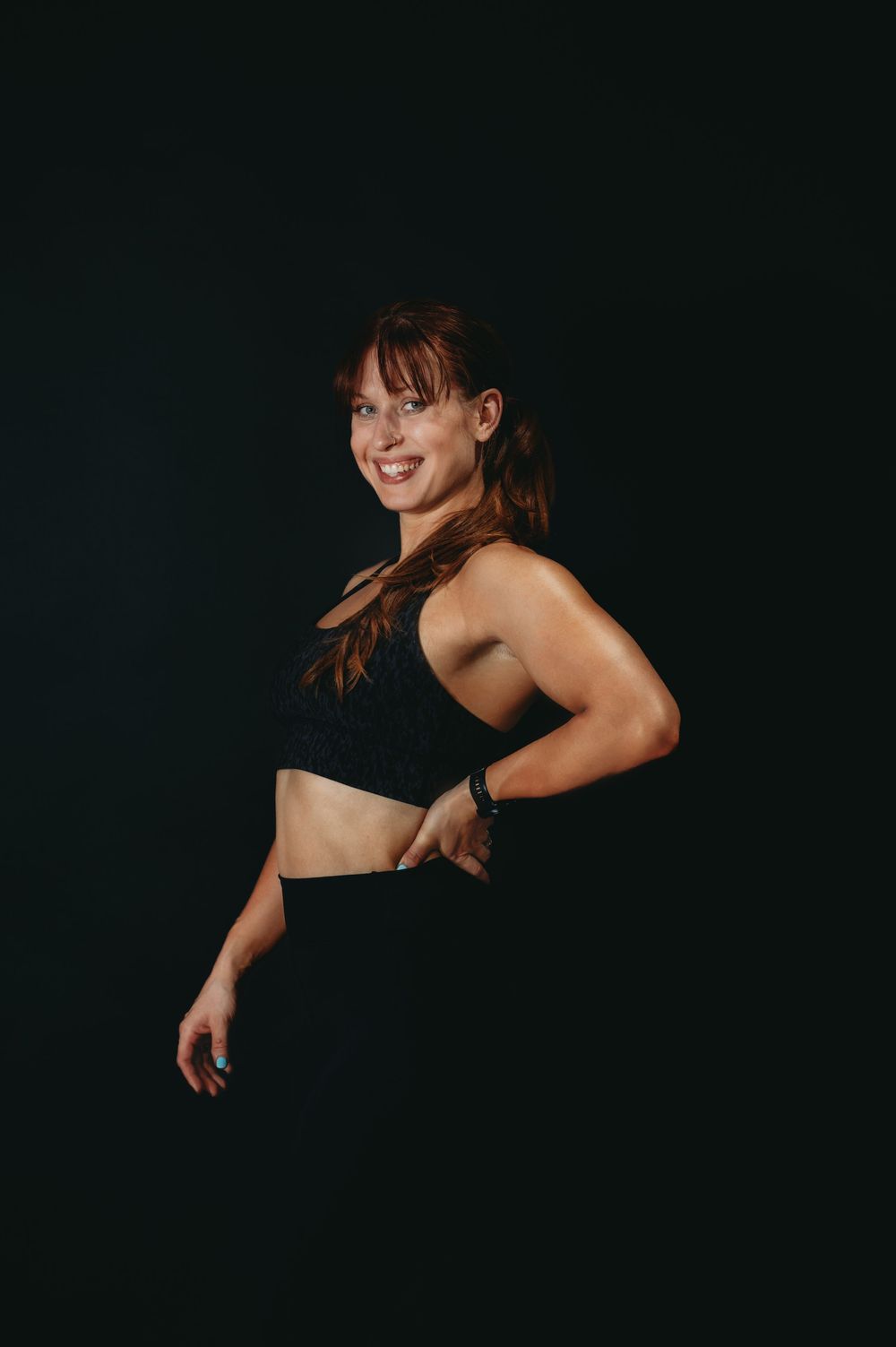 Athletic figure stretching in dramatic lighting against dark backdrop.
