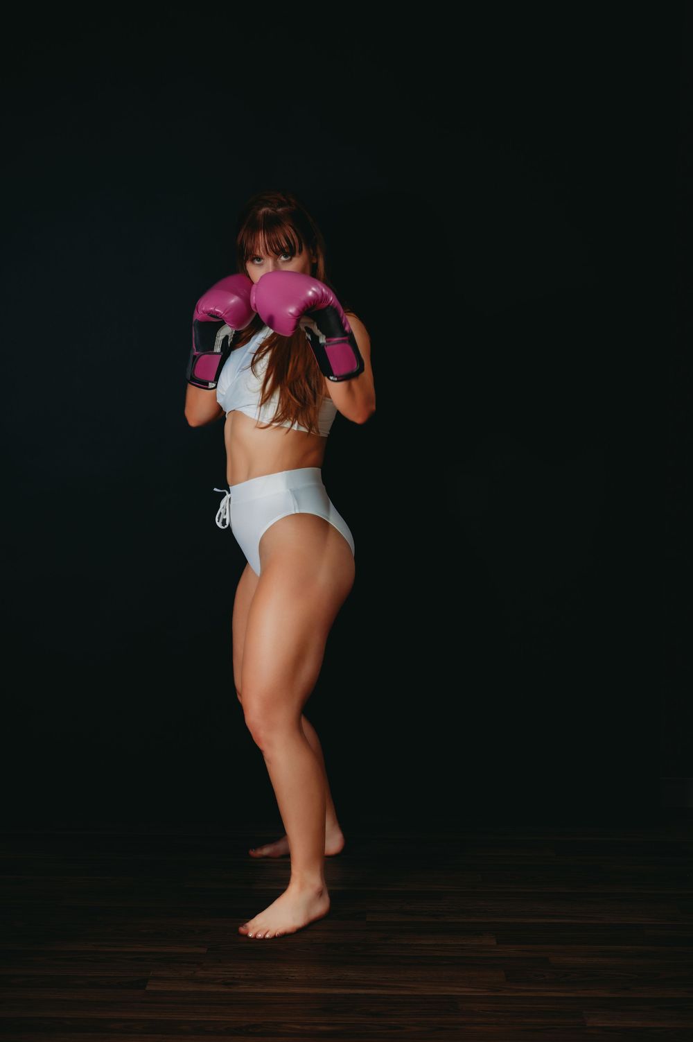 Artistic photo of someone wearing pink and white workout clothing against dark background.