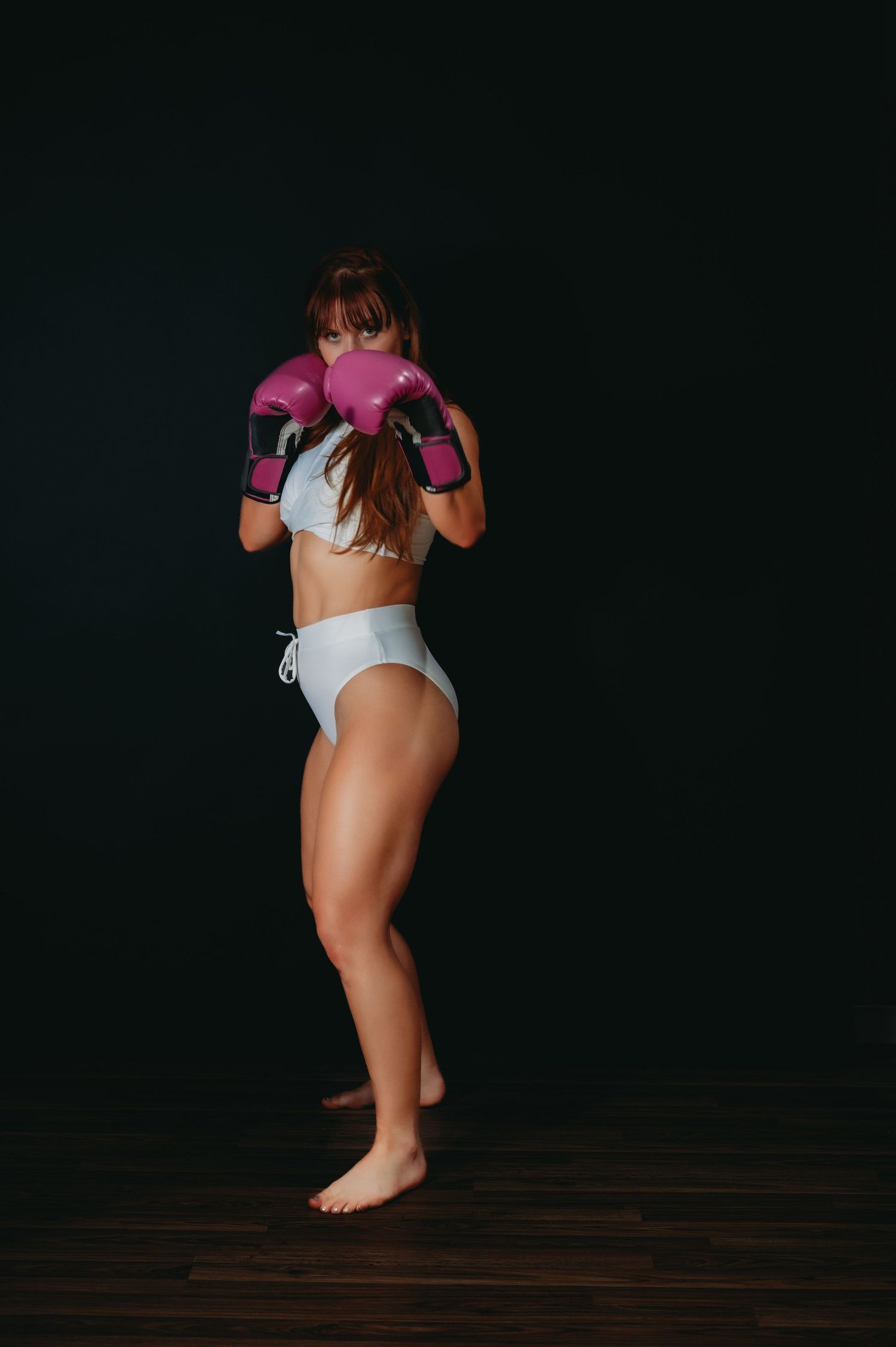 Artistic photo of someone wearing pink and white workout clothing against dark background.