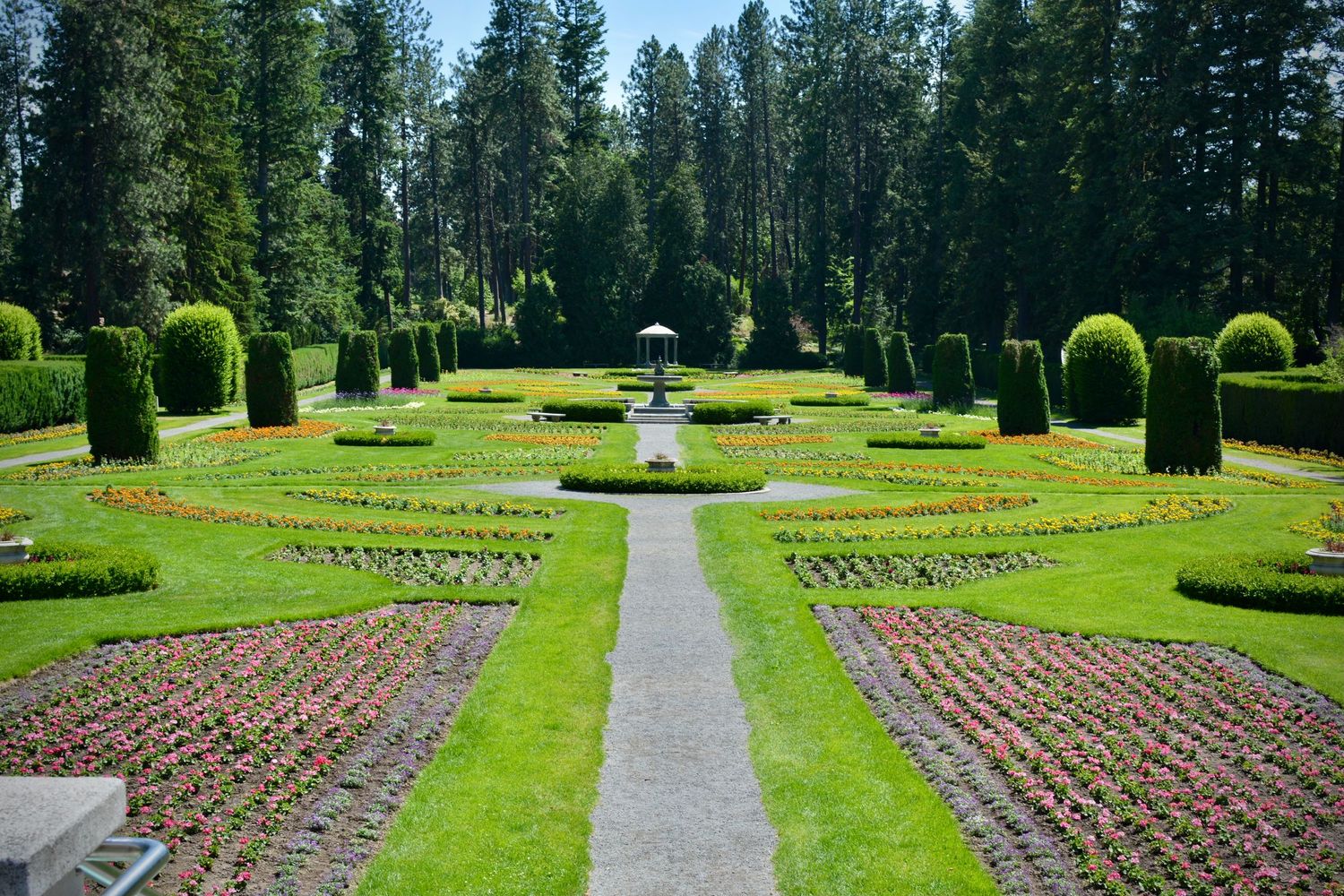 Symmetrical garden path lined with manicured lawns and evergreen trees.