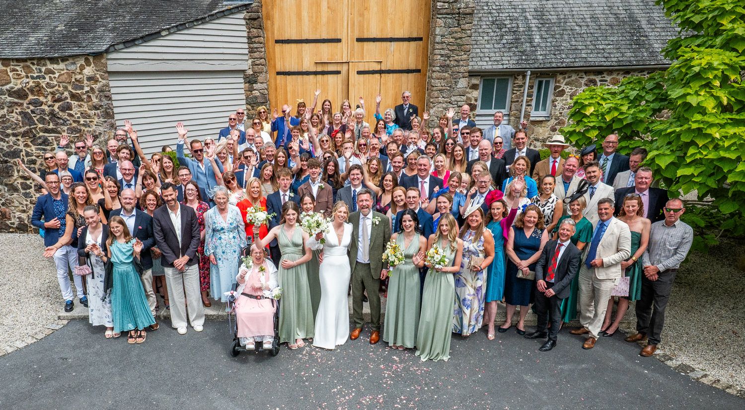 A panoramic collage of wedding guests gathered outside a rustic barn venue for group photos.
