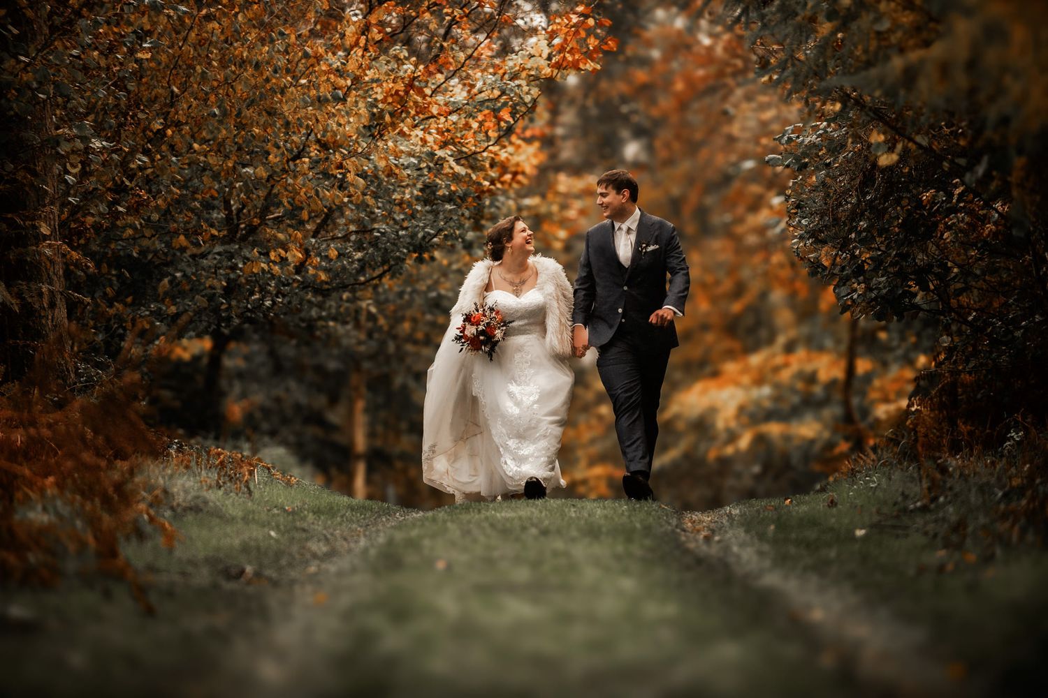 A couple walks together through a scenic autumn forest path with golden foliage and warm lighting.