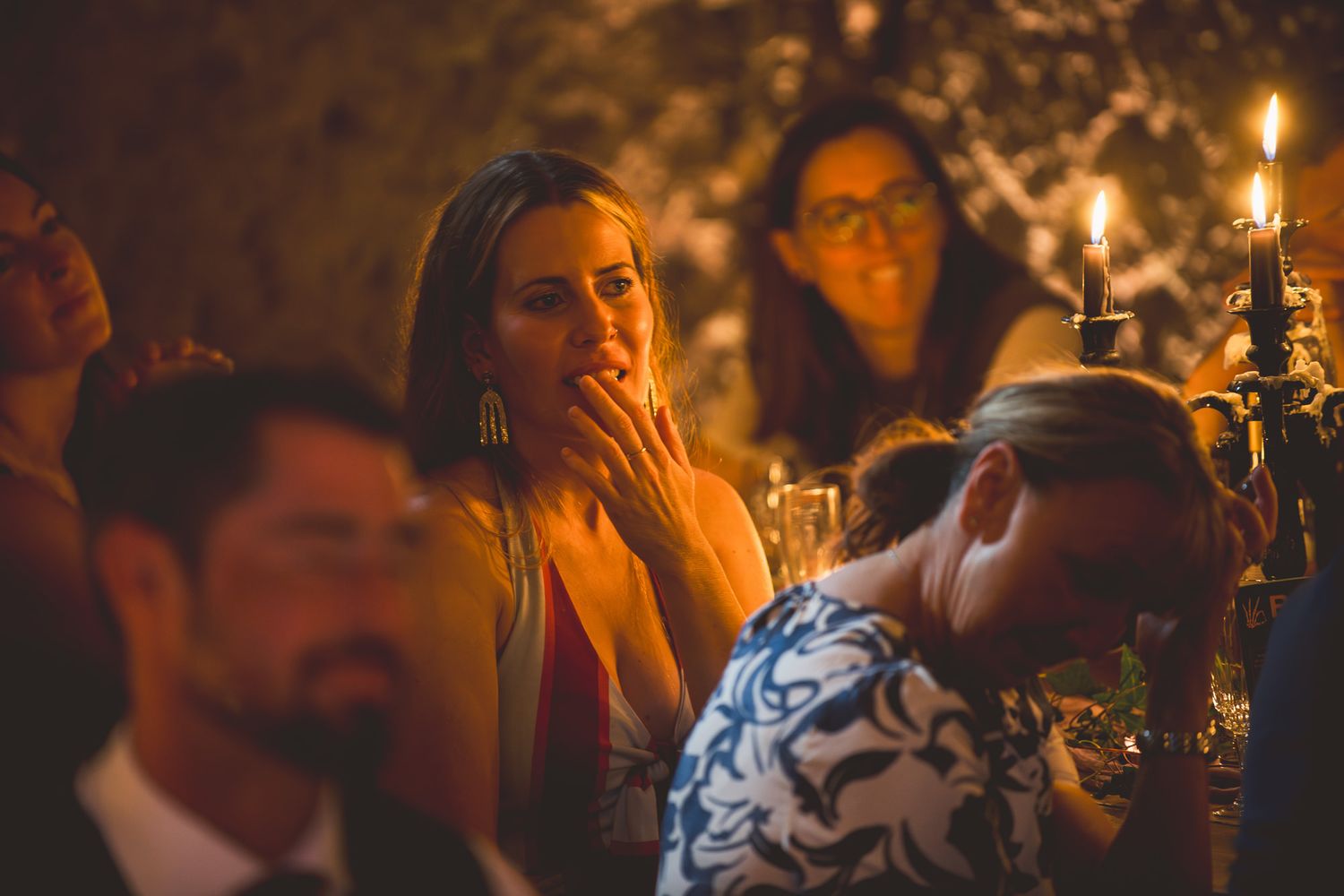 Candlelit crowd gathers at an intimate evening event with warm lighting and emotional expressions.