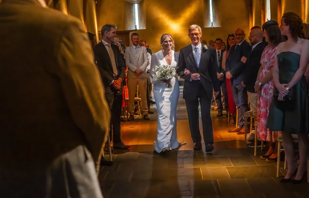 Wedding guests dance and celebrate on a dimly lit dance floor at an evening reception.
