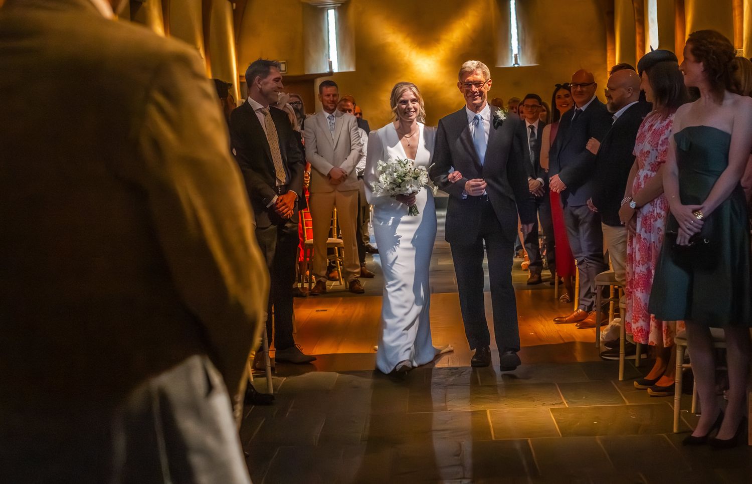 Wedding guests dance and celebrate on a dimly lit dance floor at an evening reception.