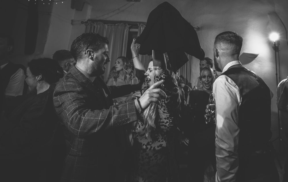 Wedding guests dance and celebrate on a dimly lit dance floor during an evening reception party.
